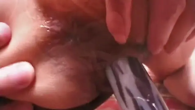 Una sexy morena japonesa de pechos generosos se entrega al placer con un consolador.